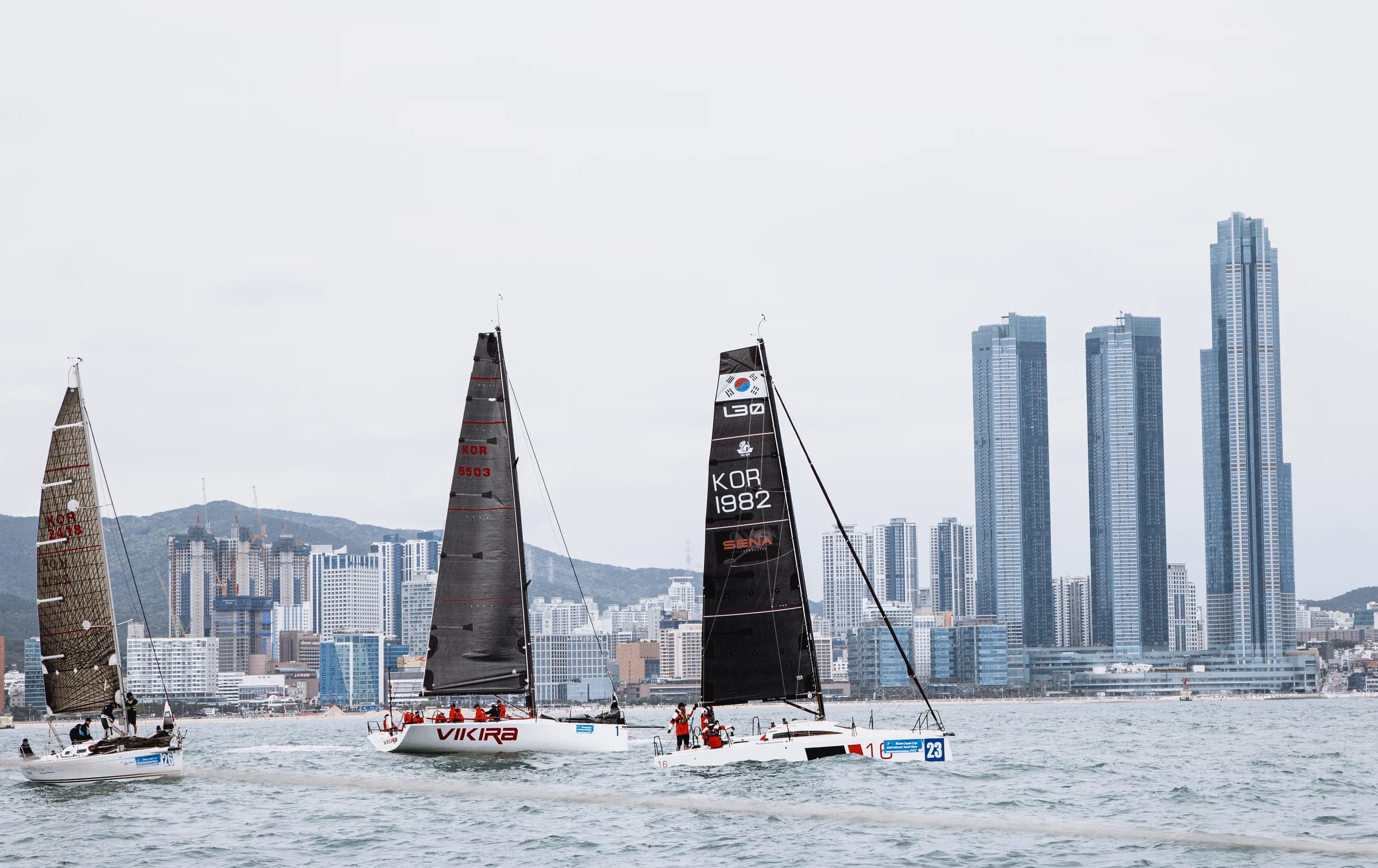Racing yachts gather against the Busan skyline.
