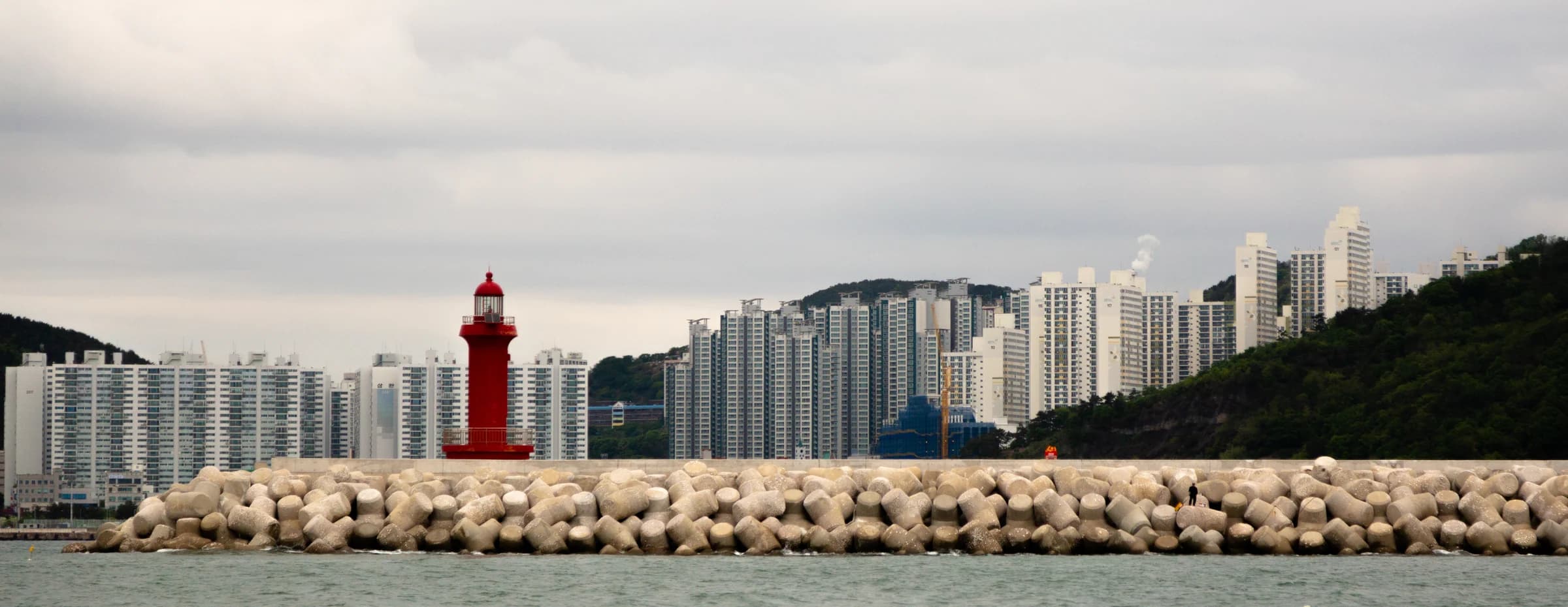 A red lighthouse and a long line of waterfront towers in Busan.