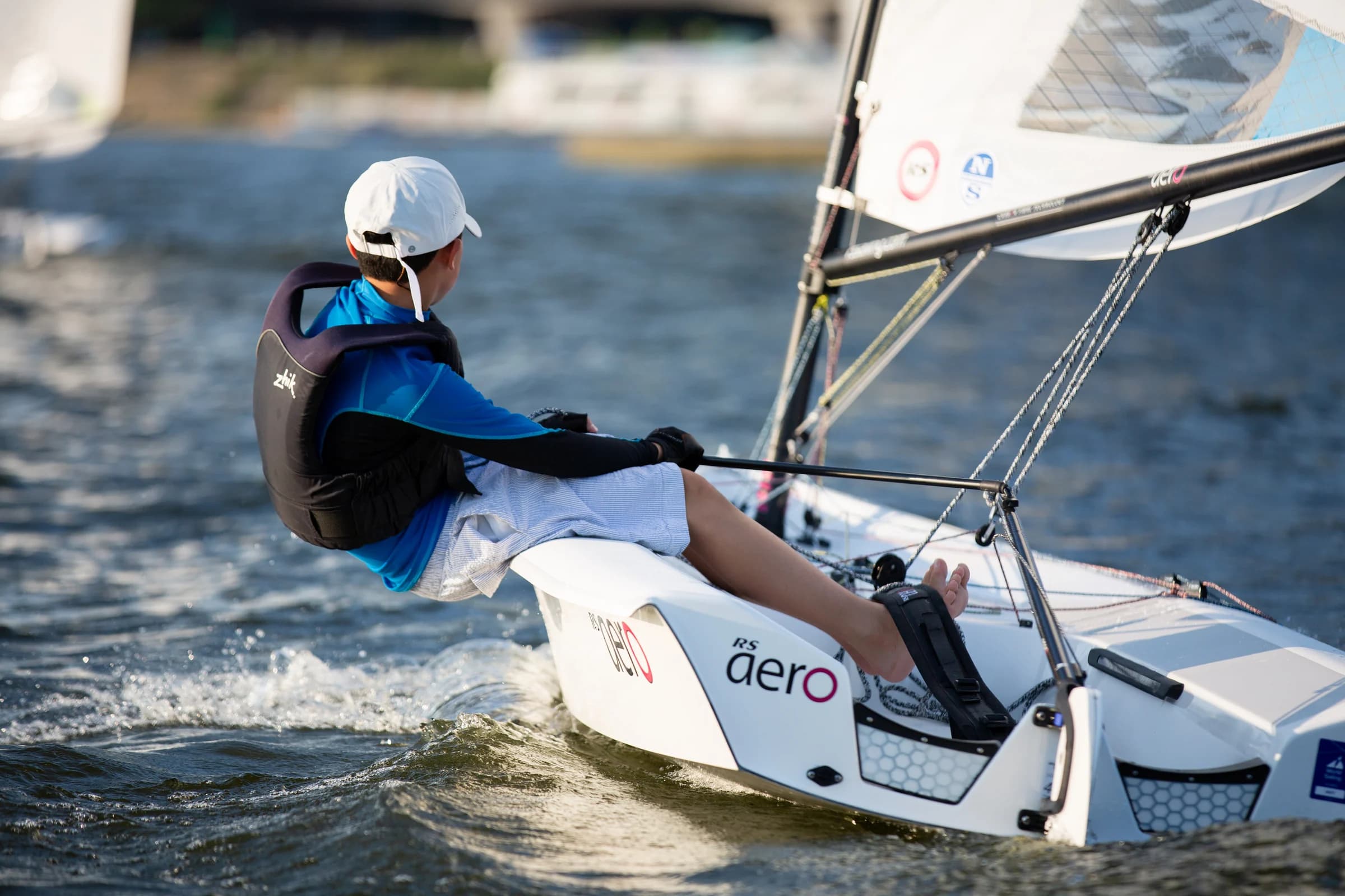 A sailor leans out over the water in an RS Aero dinghy.