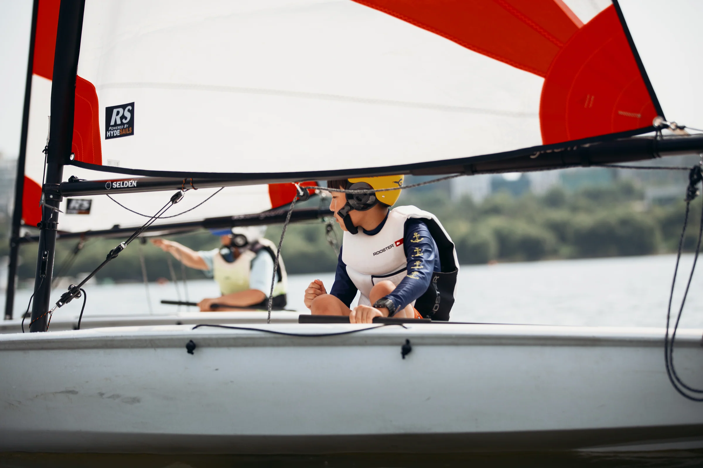 A dinghy sailor seen beneath a bold red and white sail.