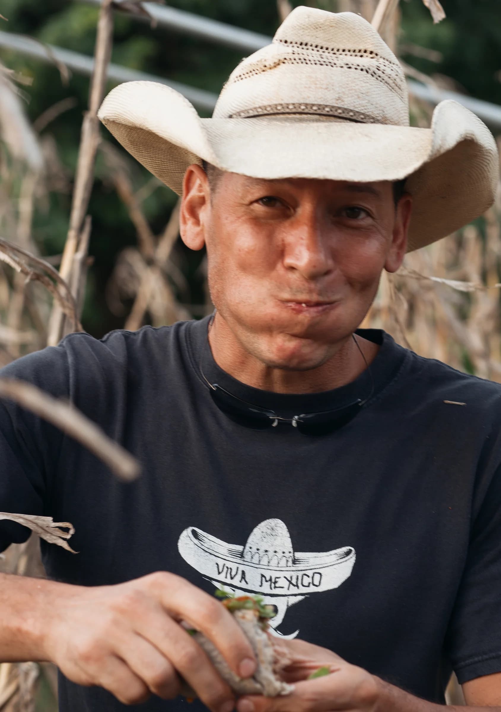 A man in a straw hat enjoying a meal outdoors.